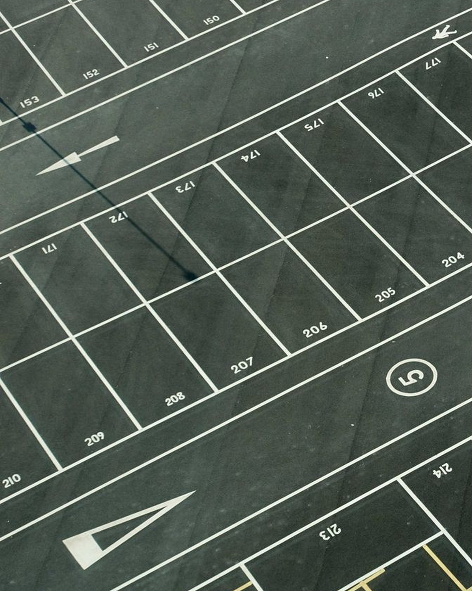 Close aerial crop of numbered parking stalls and aisle lines painted on dark asphalt