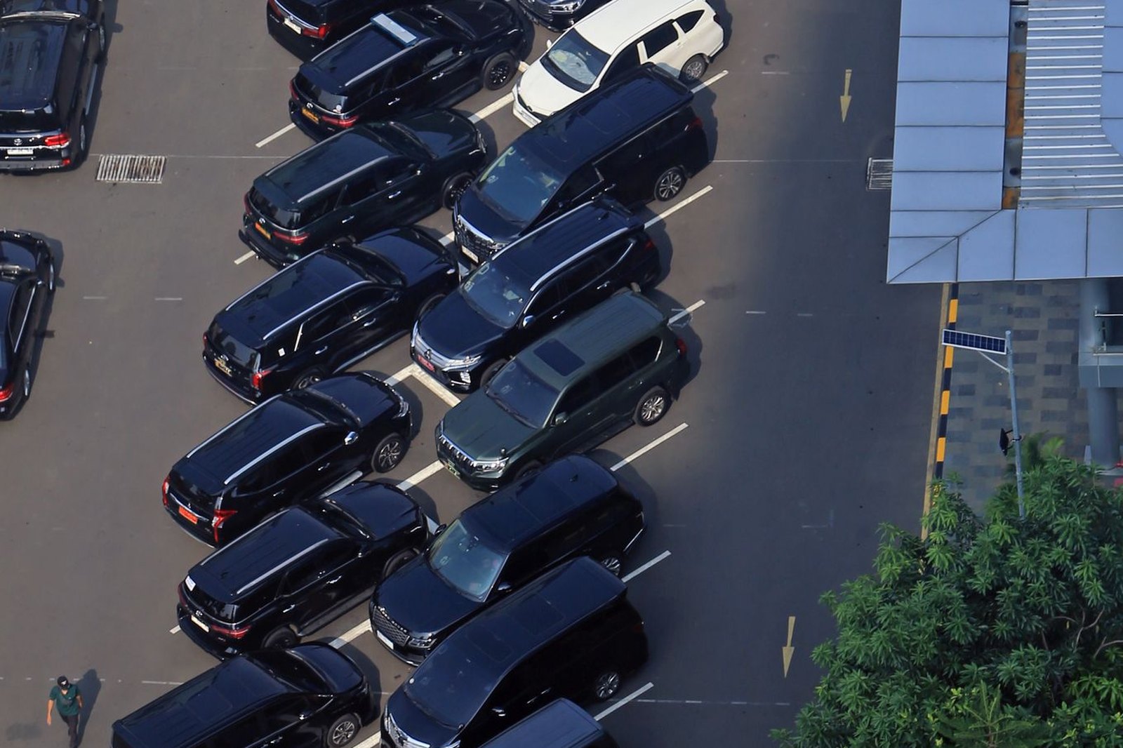 Aerial crop of tightly parked rows of vehicles separated by a marked drive aisle