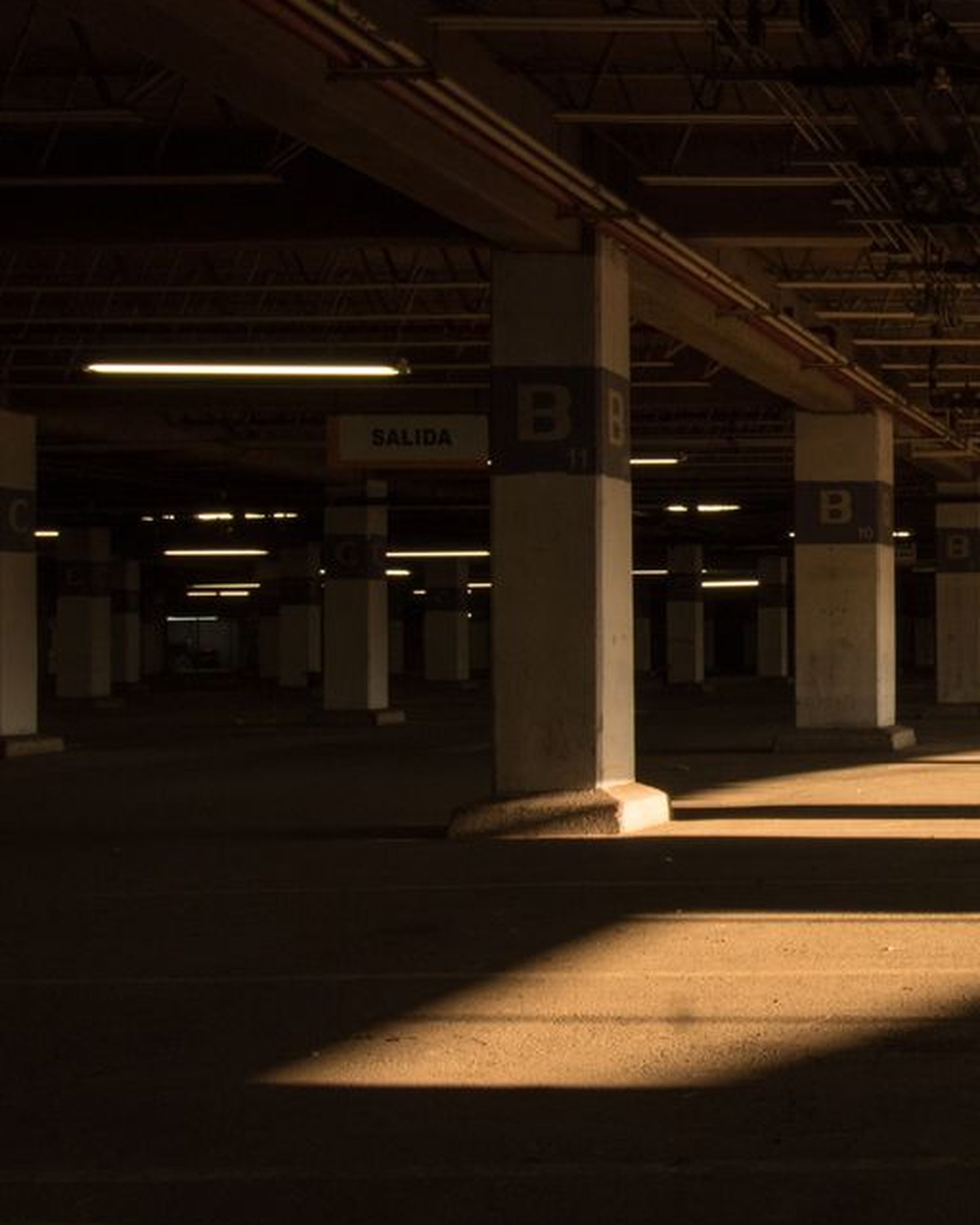 Lettered zone column and exit sign inside a lit parking structure level